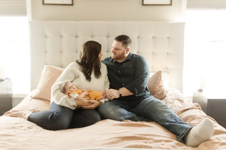 couple posing on their bed with baby, eagan mn newborn baby photographer