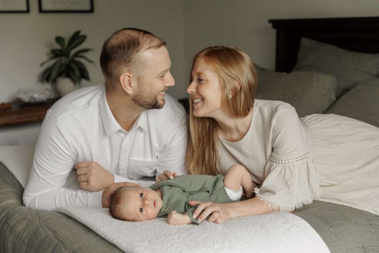 mom and dad on bed with newborn baby boy