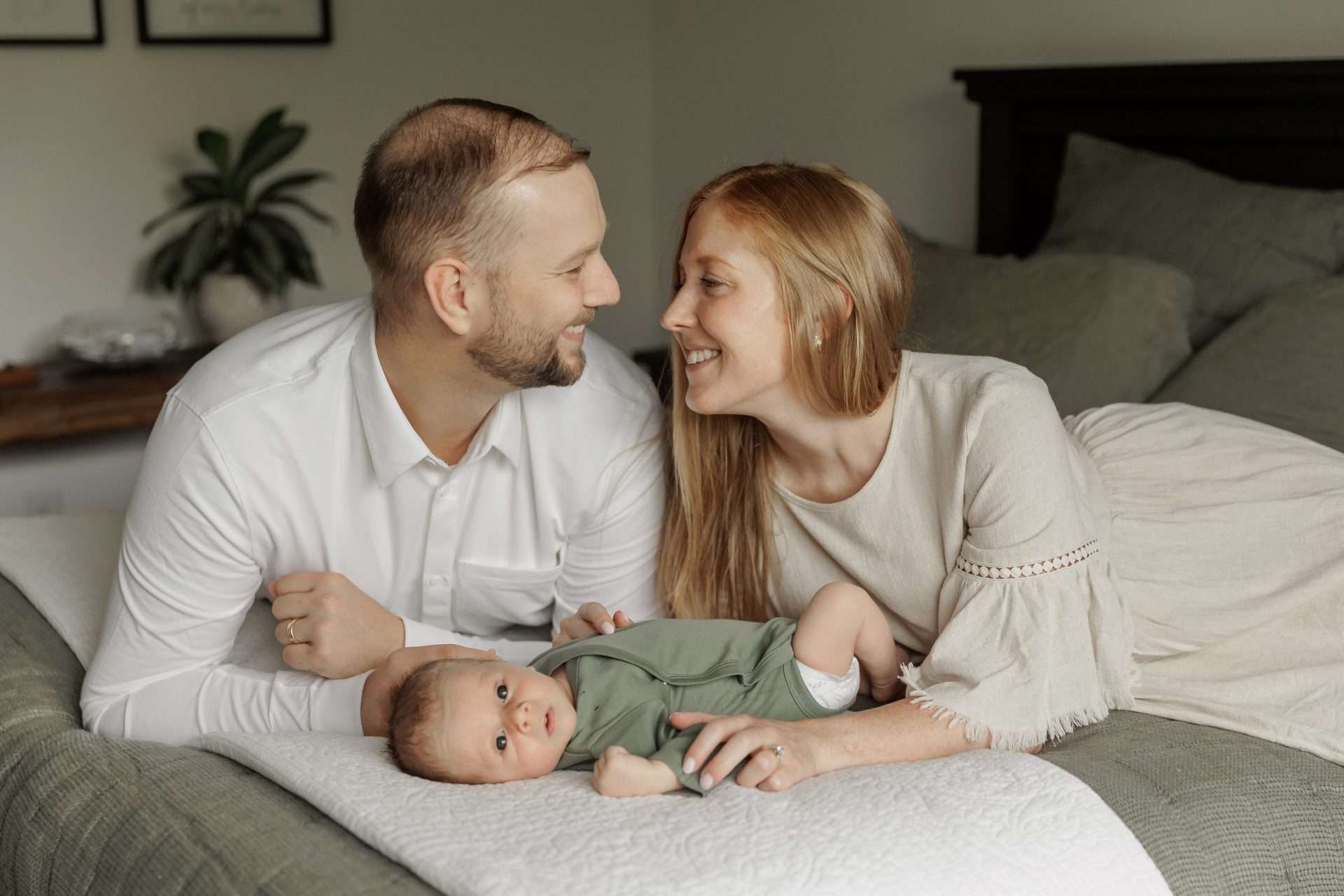 mom and dad on bed with newborn baby boy