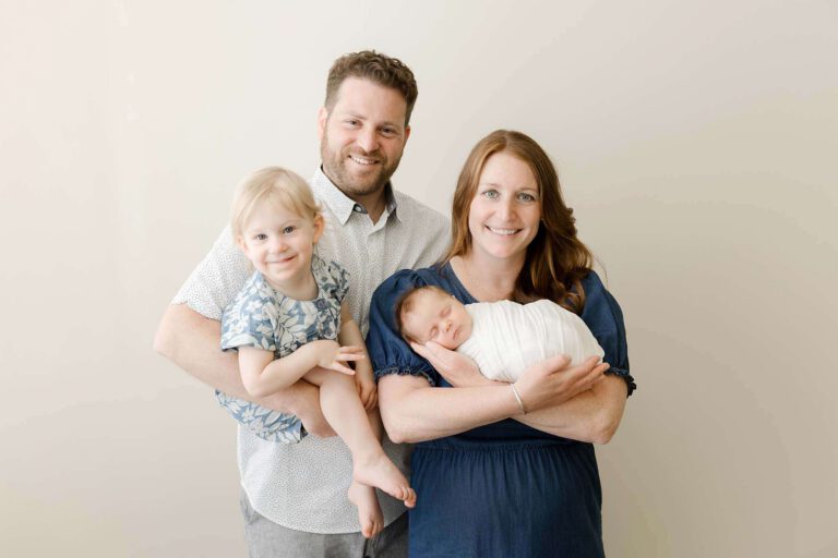 family of four posing for newborn and family photos in minneapolis studio