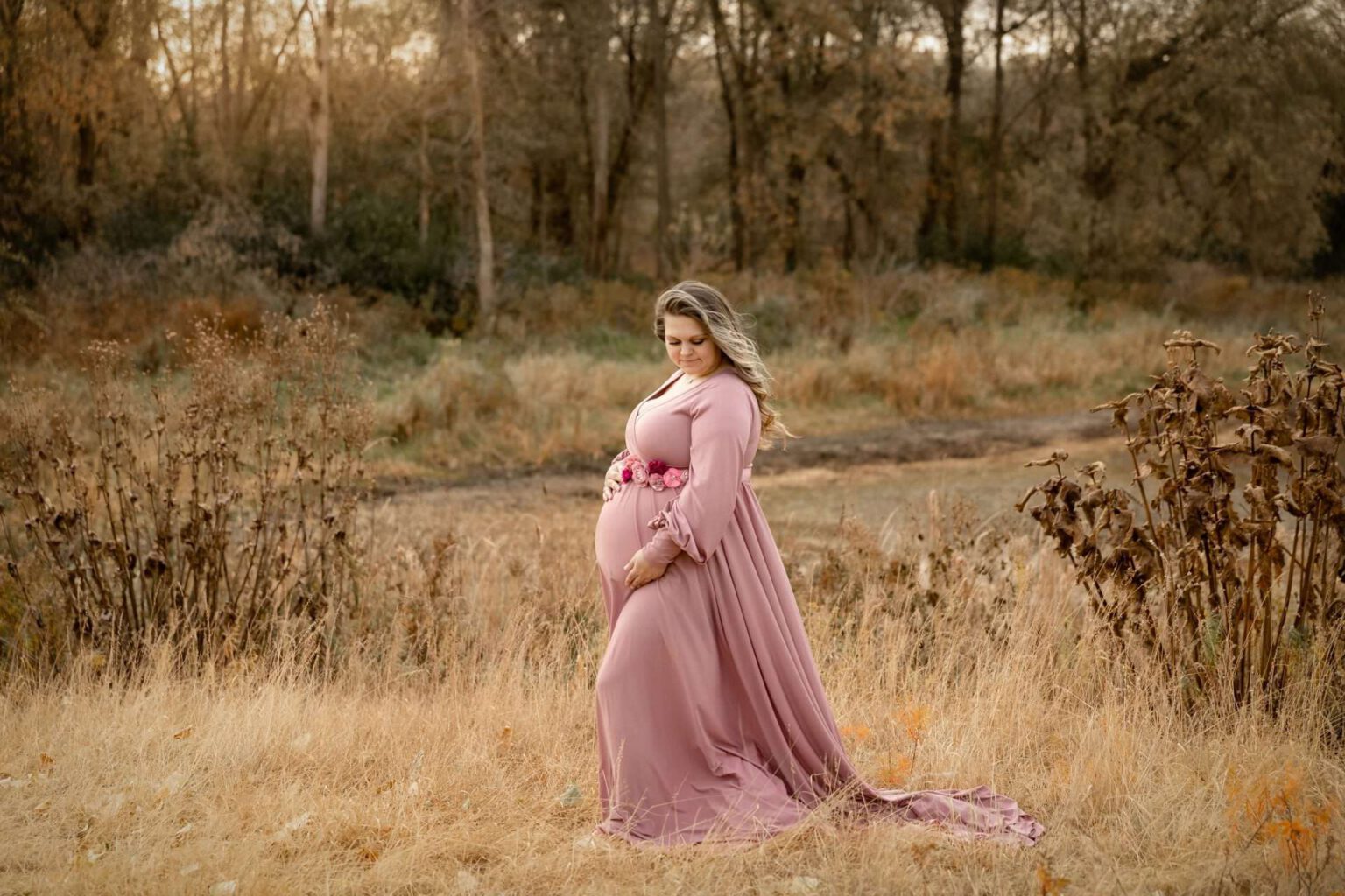pregnant woman in pink flowy dress in field in minneapolis mn