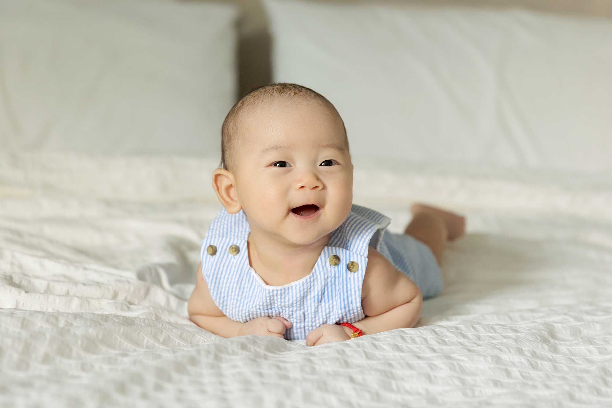 100 day old baby boy posing on bed