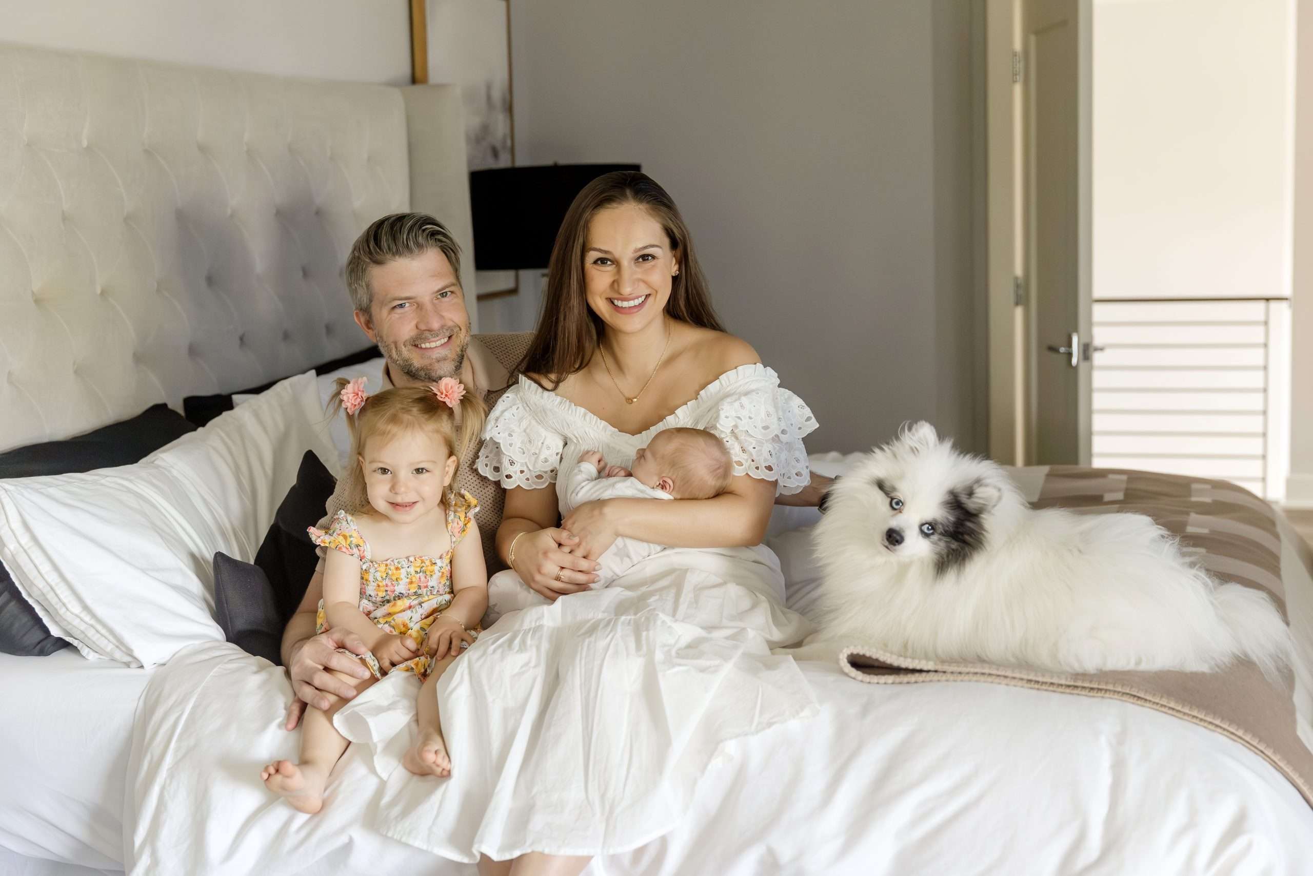 family of four with dog posing on bed with newborn in edina mn