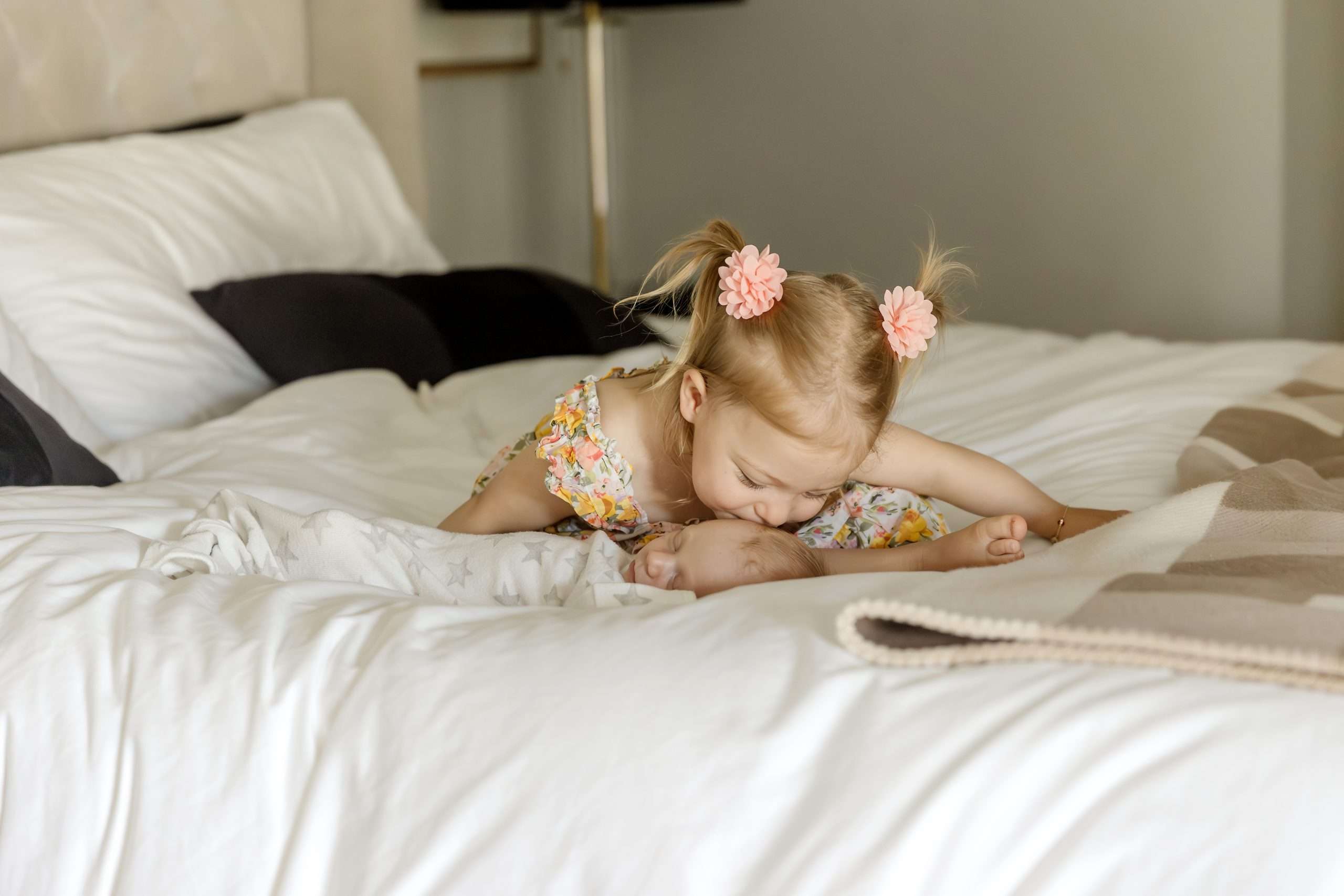 big sister kissing little baby brother on bed for newborn photos in edina mn