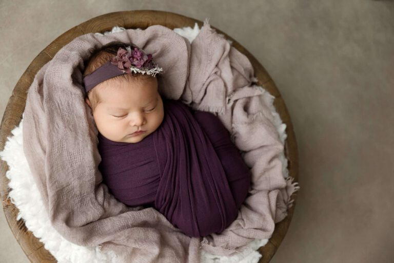 swaddled newborn in purple