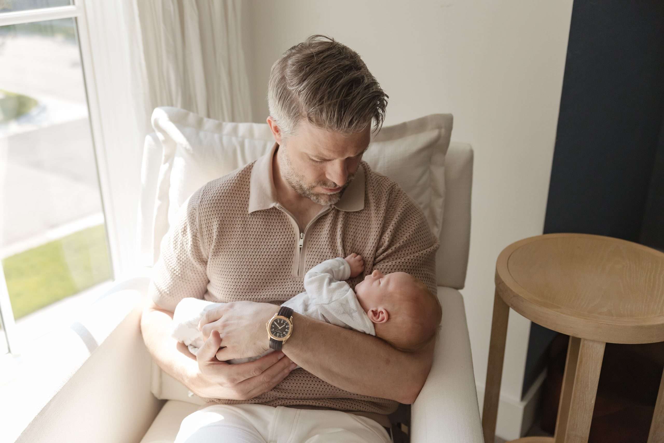 dad holding newborn in rocking chair in nursery in edina mn