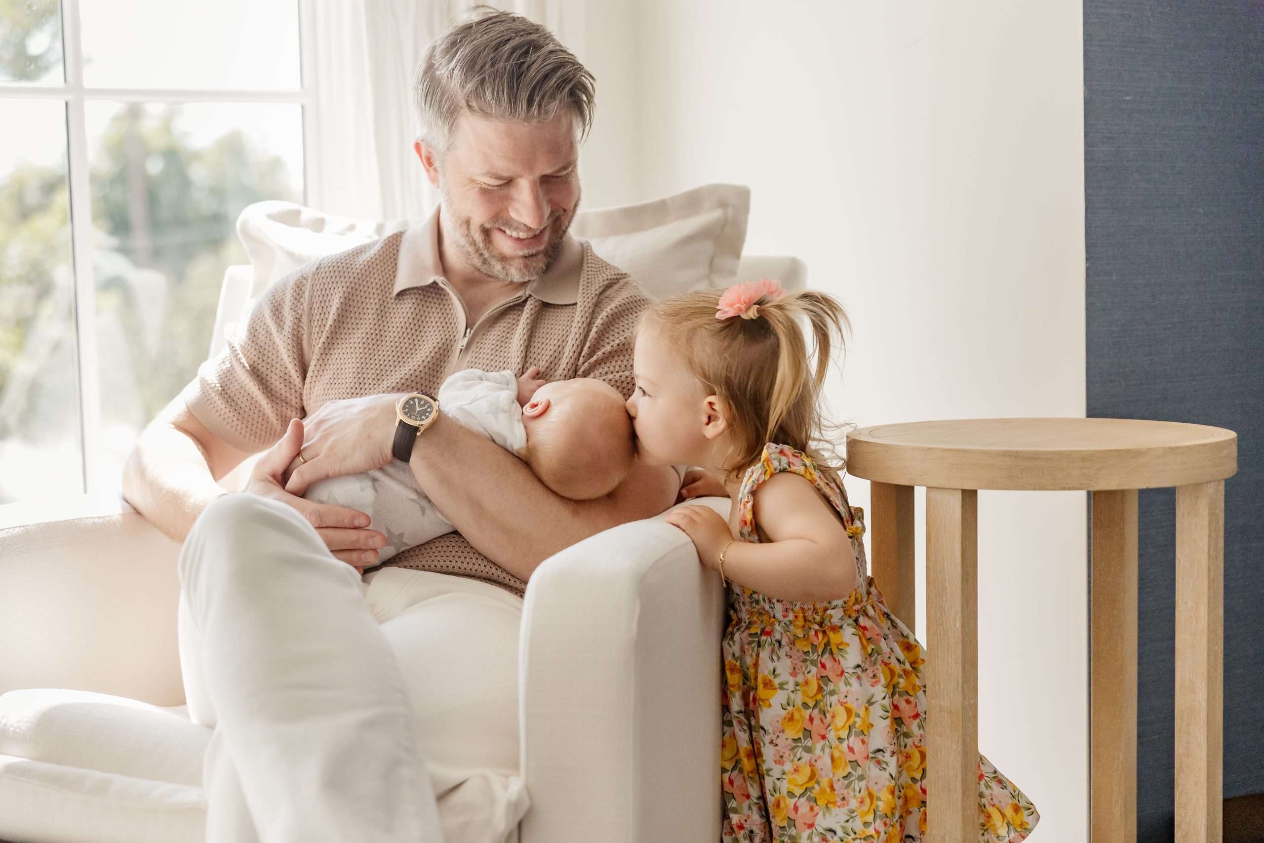 dad holding newborn baby while toddler kisses baby's head in edina mn