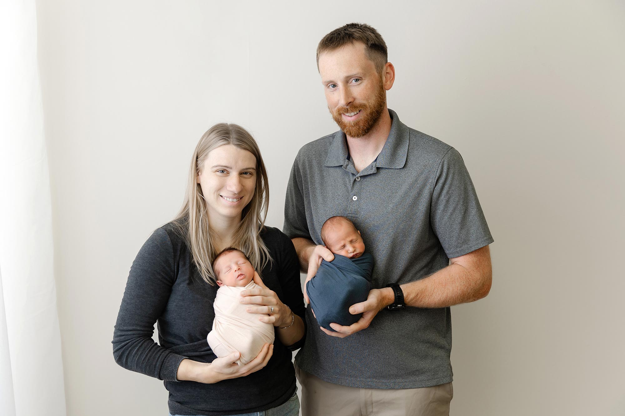 mom and dad holding twin newborn babies in a studio