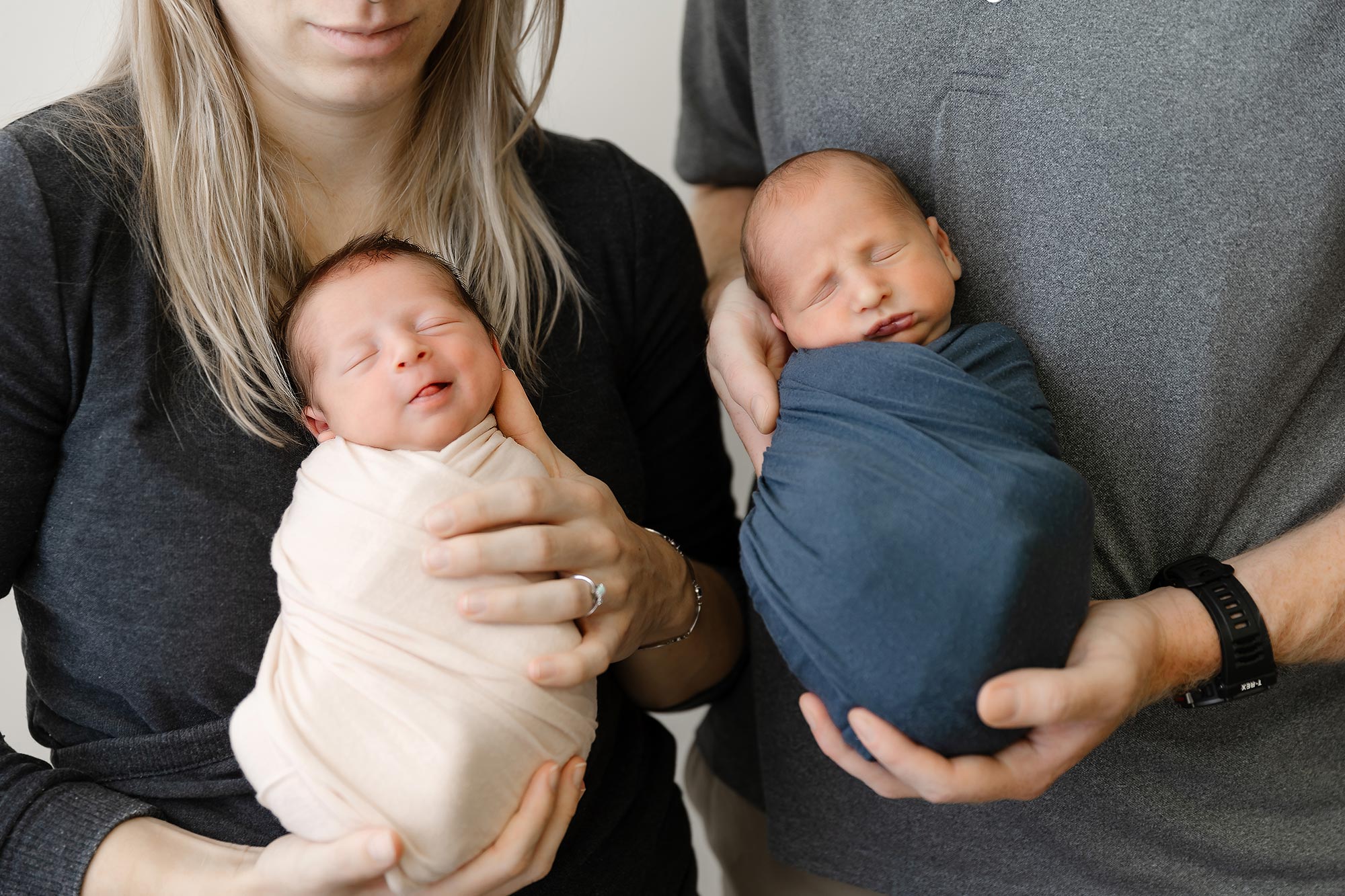 close up of newborn twins held by parents