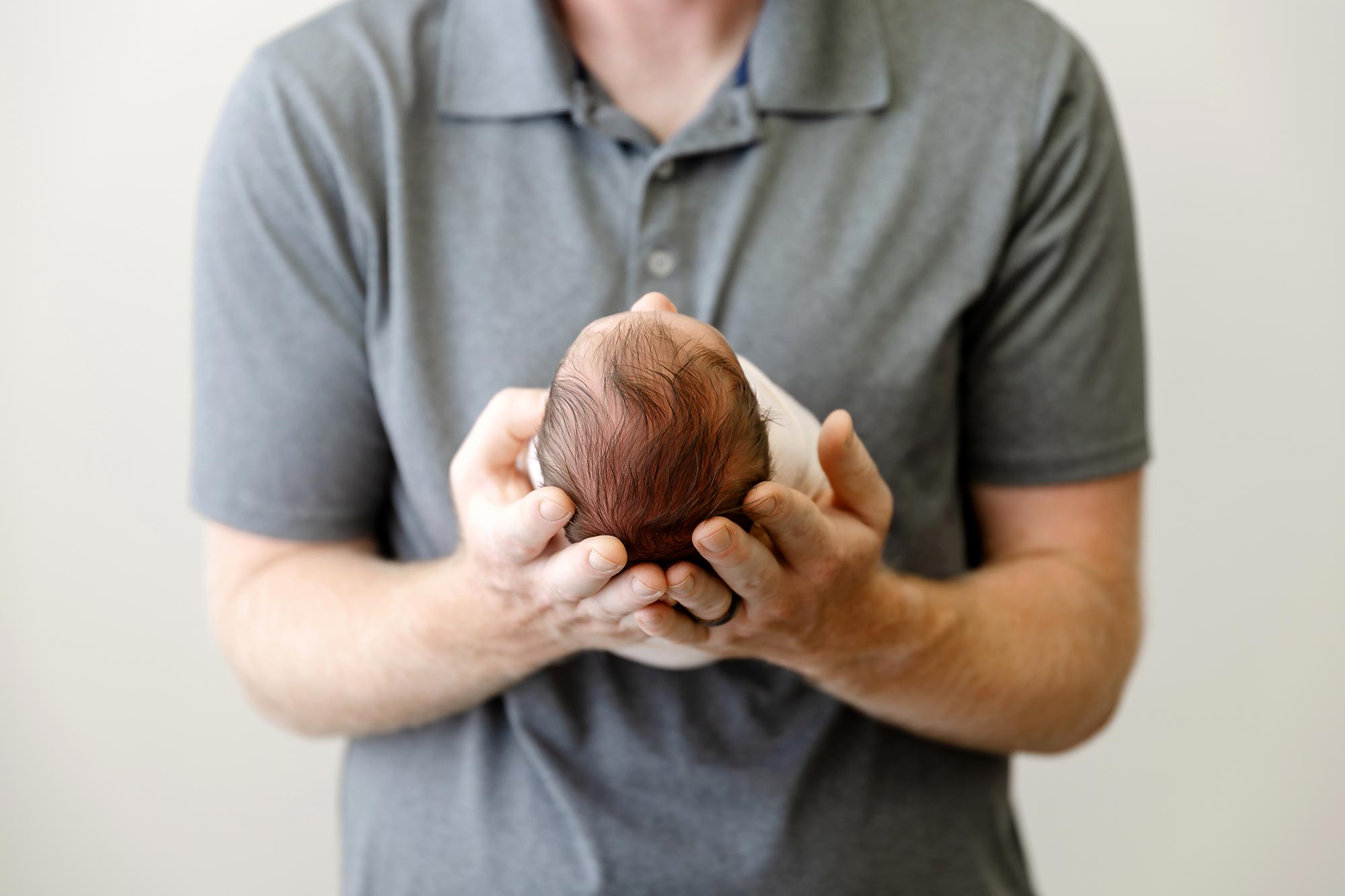 top of newborn head with dad holding newborn baby