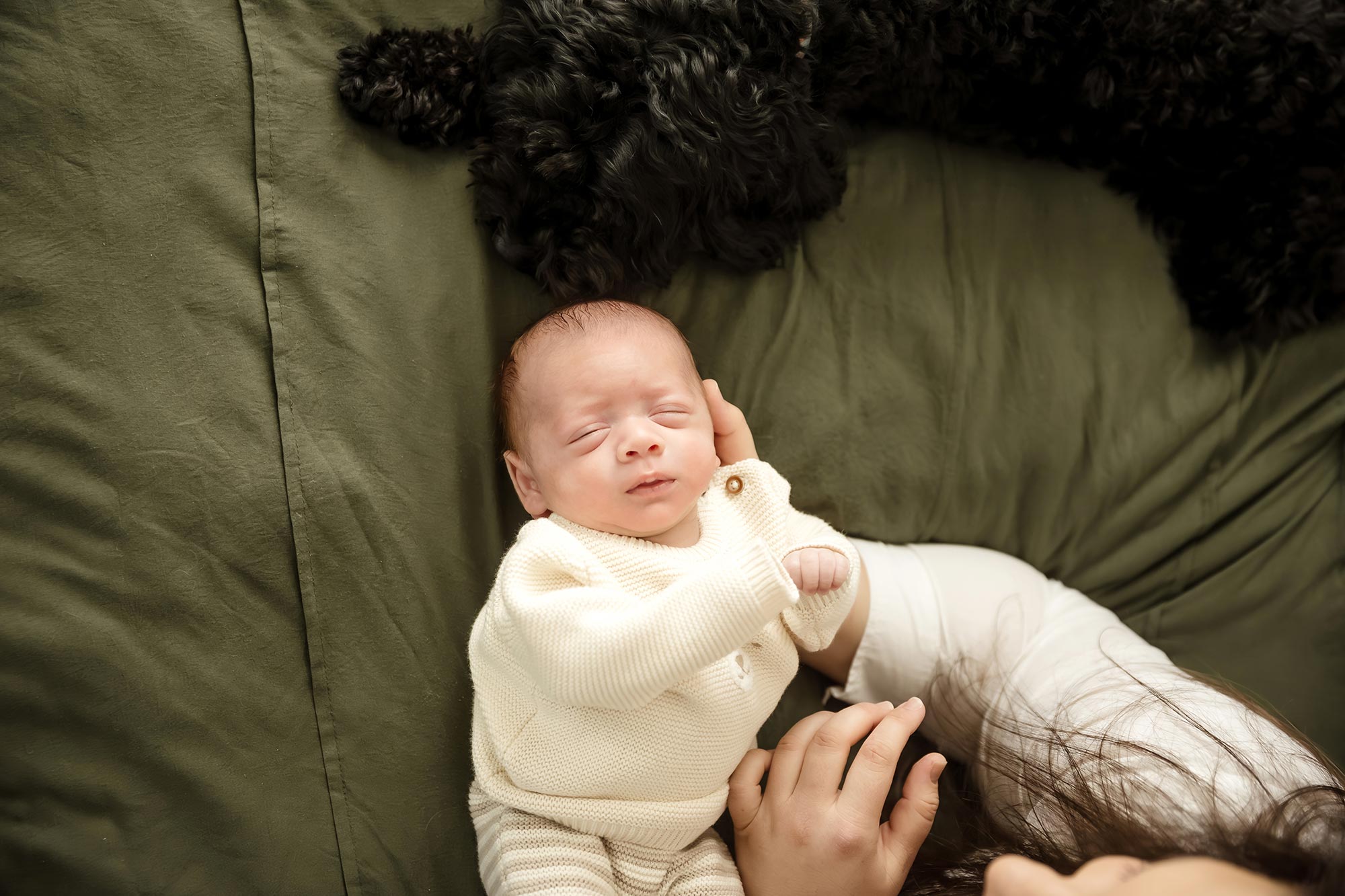 newborn boy in cream top and pants for photos at home in minneapolis mn