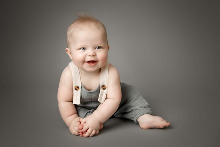 6 month baby boy sitting on grey backdrop for maple grove baby photographer