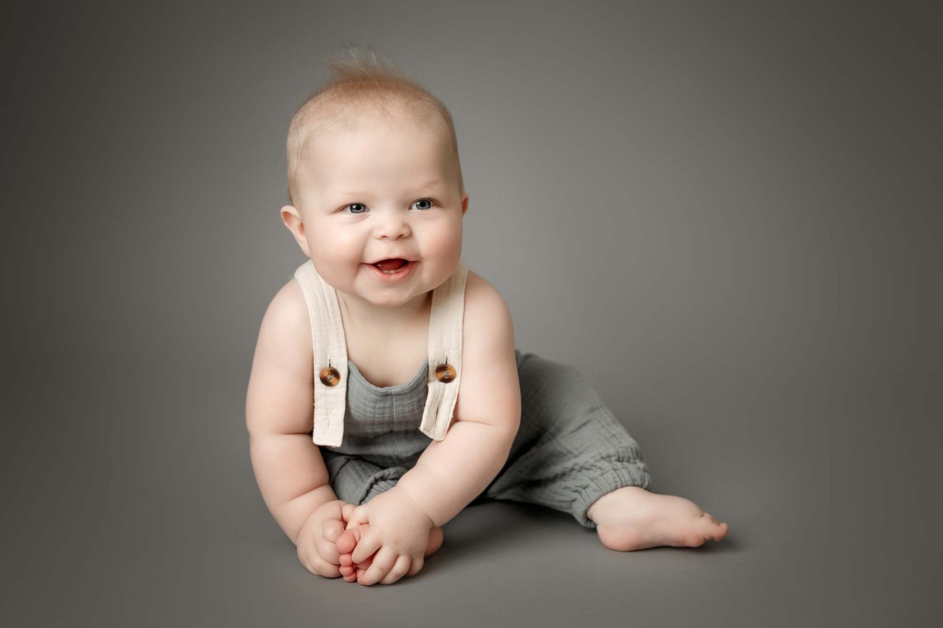 6 month baby boy sitting on grey backdrop for maple grove baby photographer
