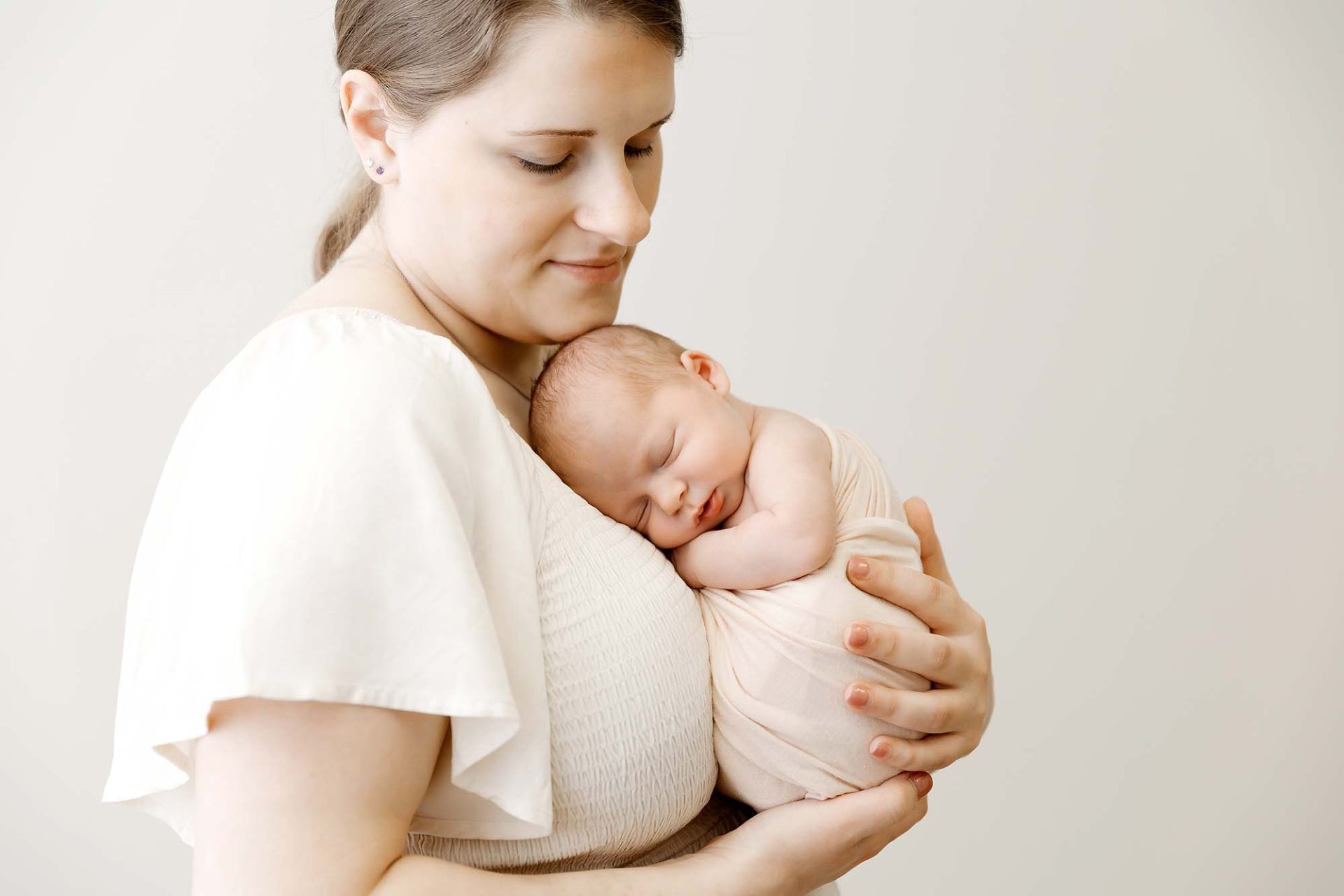 mom holding her newborn baby at a minneapolis newborn photography studio