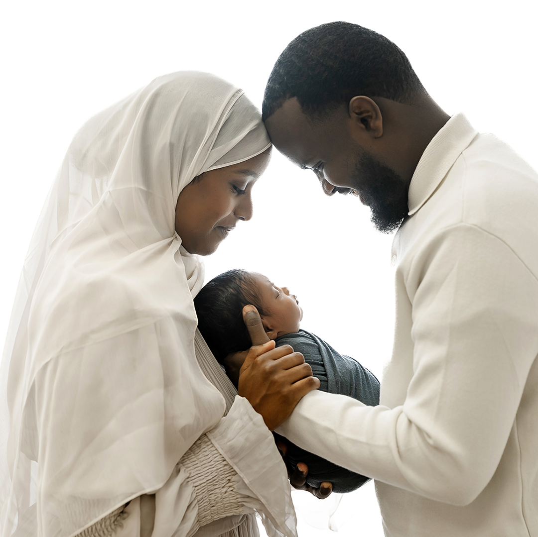 mom and dad holding baby boy between them looking down on white backdrop