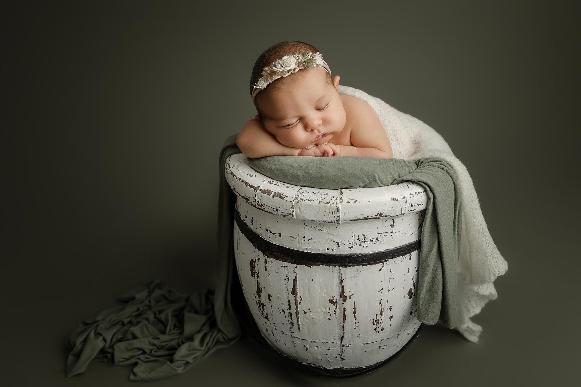 newborn baby girl posed in bucket in green and cream at newborn photography studio in minneapolis mn