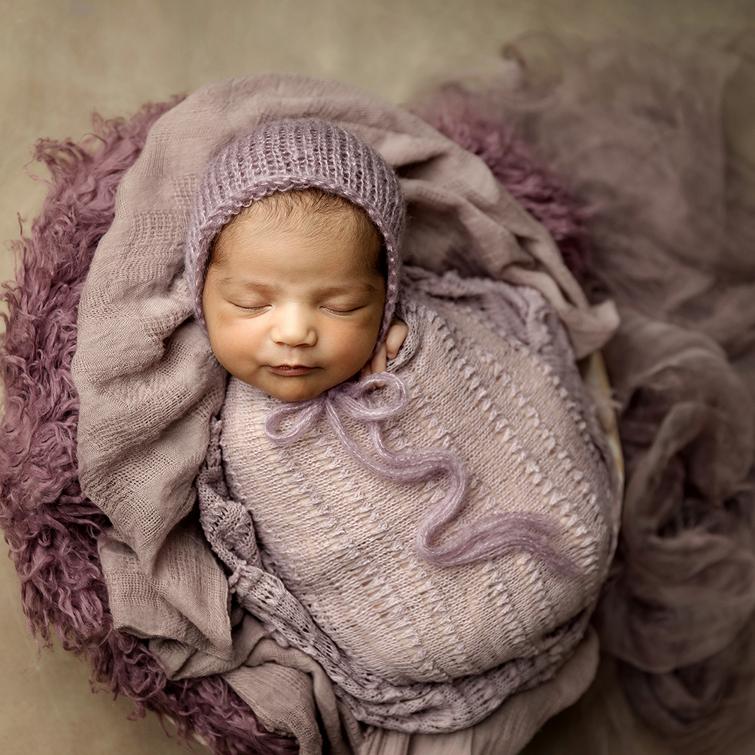 newborn girl wrapped in purple