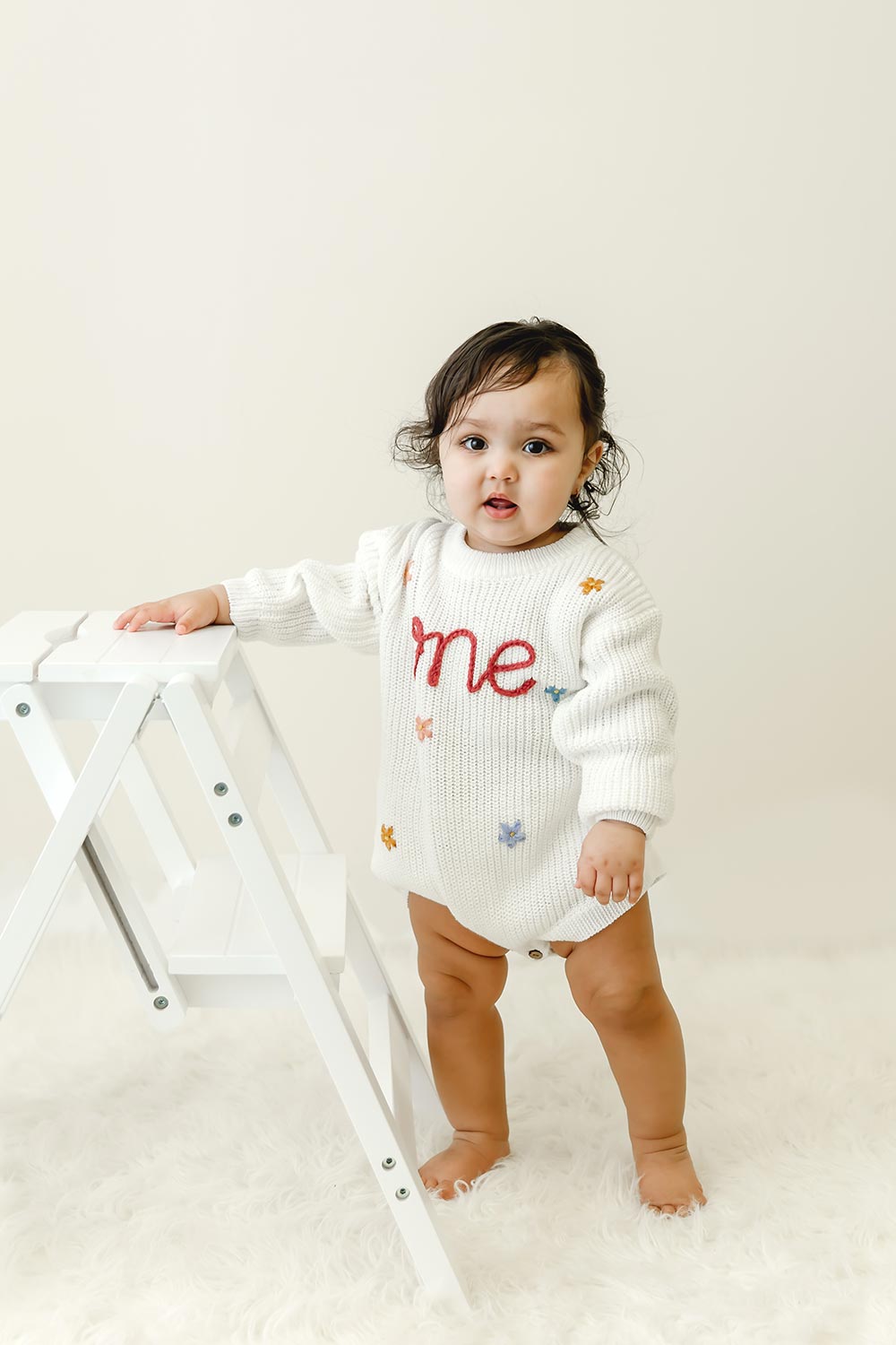 one year baby girl posing on white rug in minneapolis portrait studio