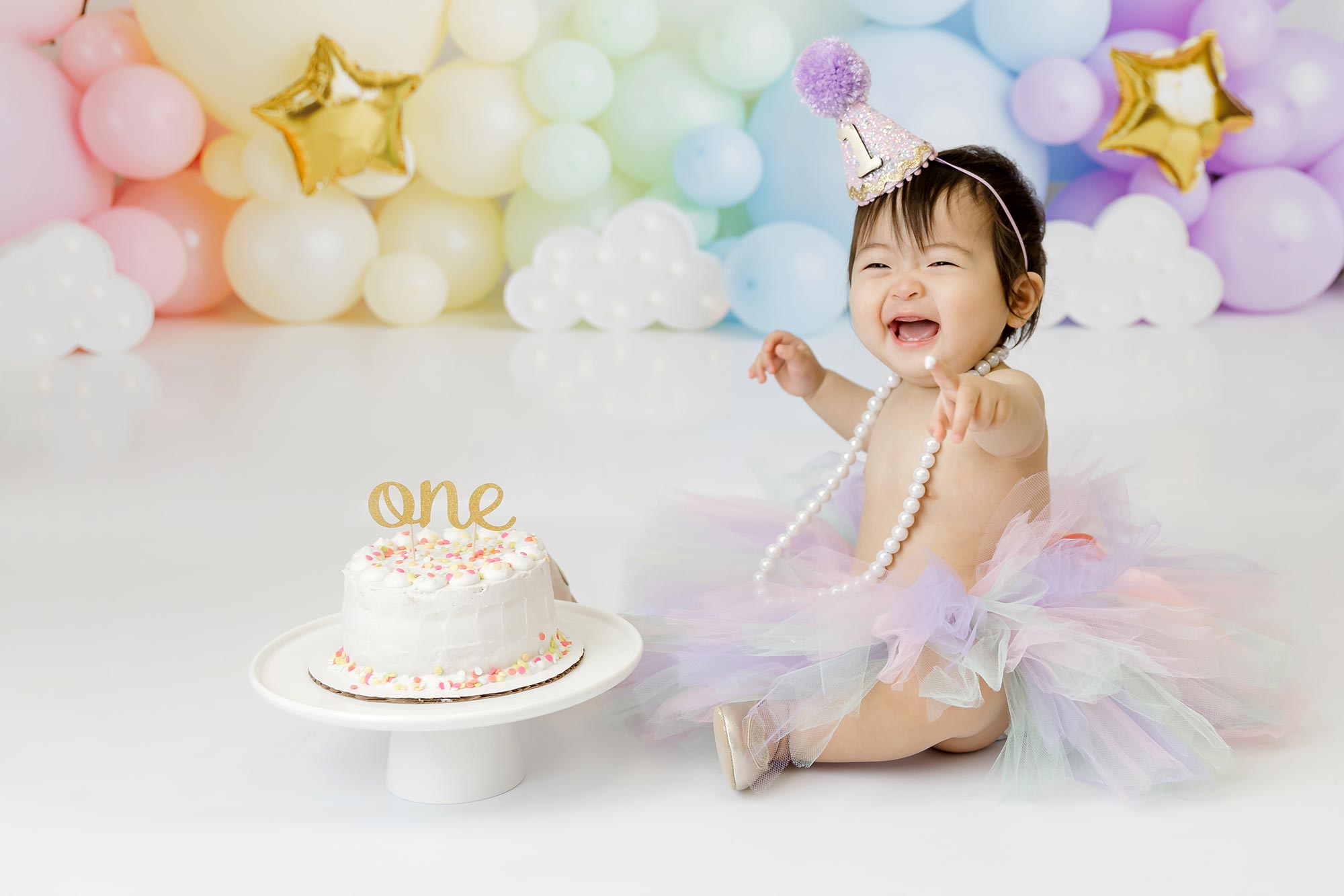 rainbow themed first birthday cake smash with one year old baby girl in minneapolis studio