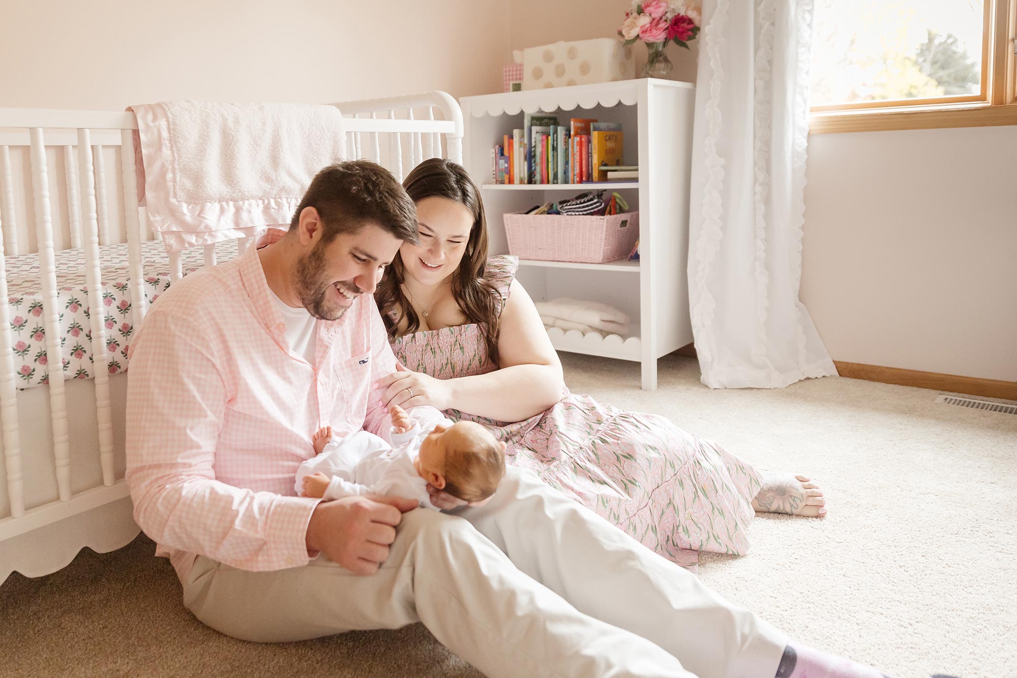 couple sitting on floor in nursery holding newborn girl in minneapolis
