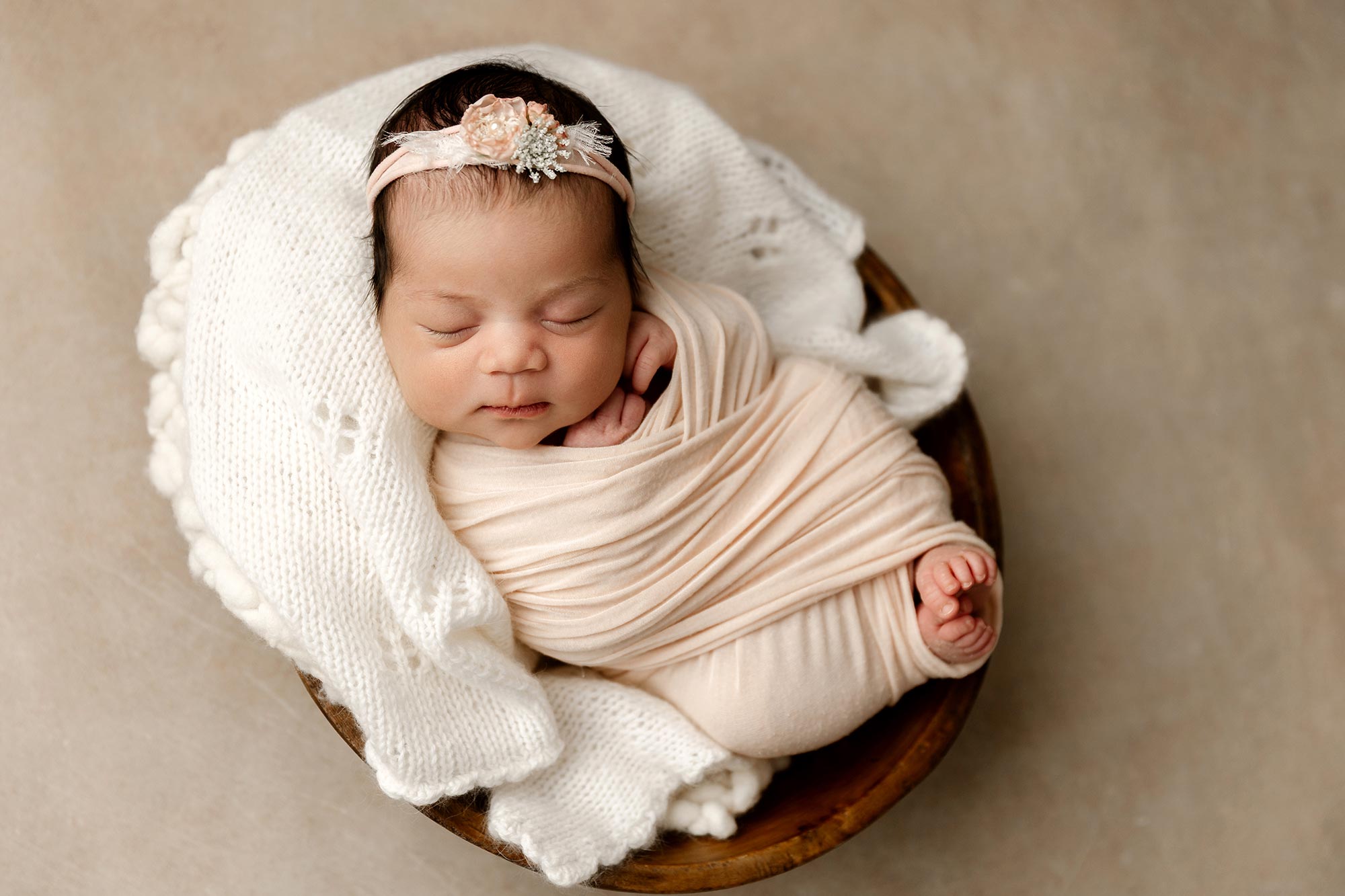 newborn girl wrapped in pink in small wooden bowl in minneapolis mn
