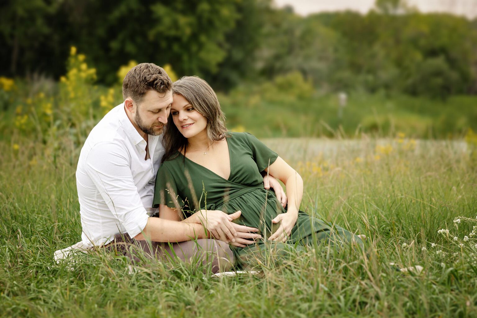 pregnant couple lying in field in the twin cities