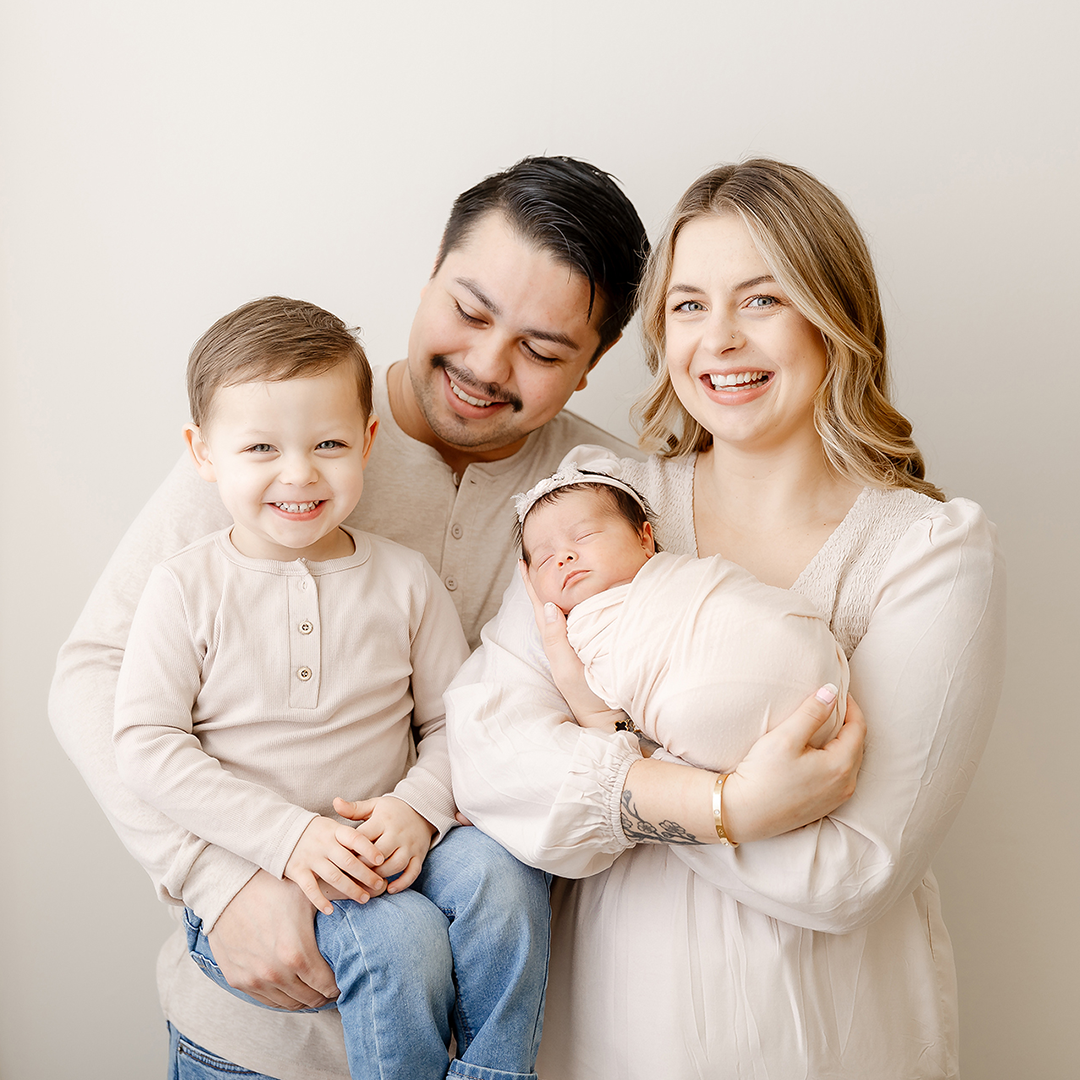 family of four posing in newborn photography studio