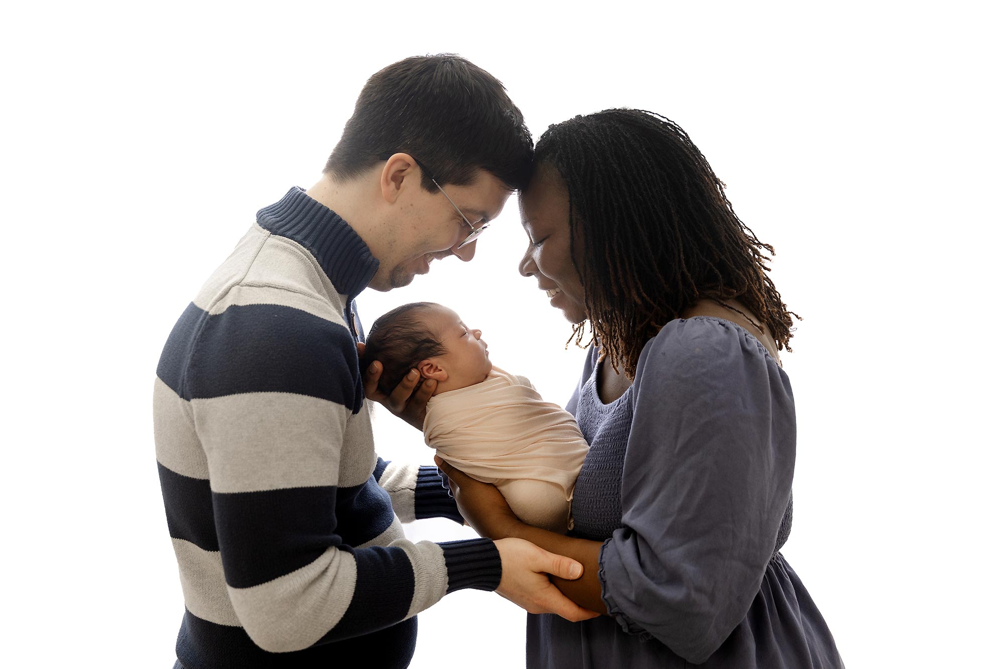 backlit image of couple holding their newborn in the studio in plymouth mn