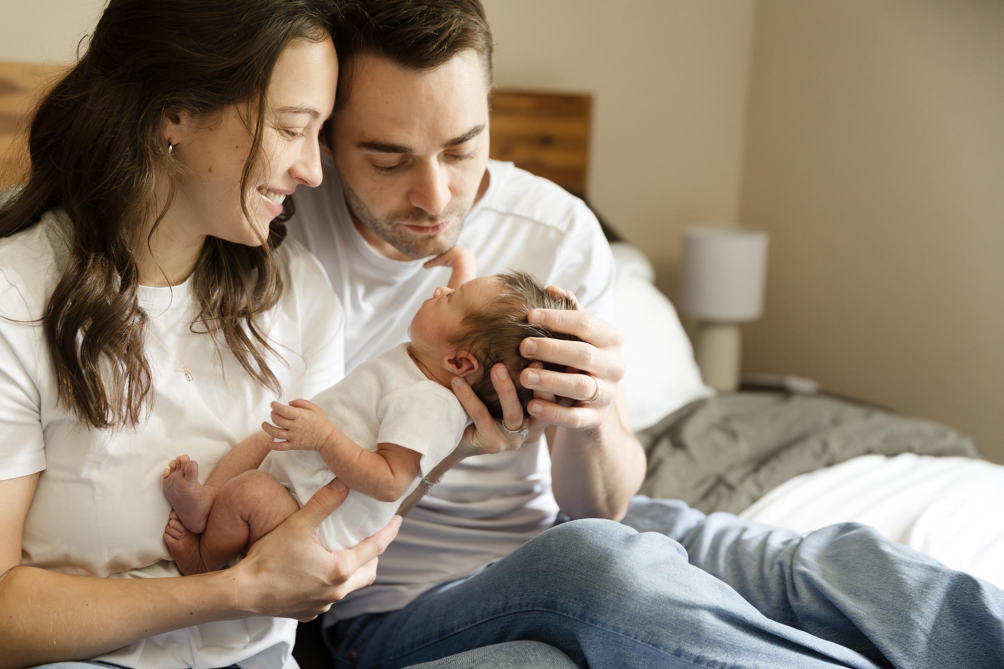 couple holding their newborn baby in bed in minneapolis mn