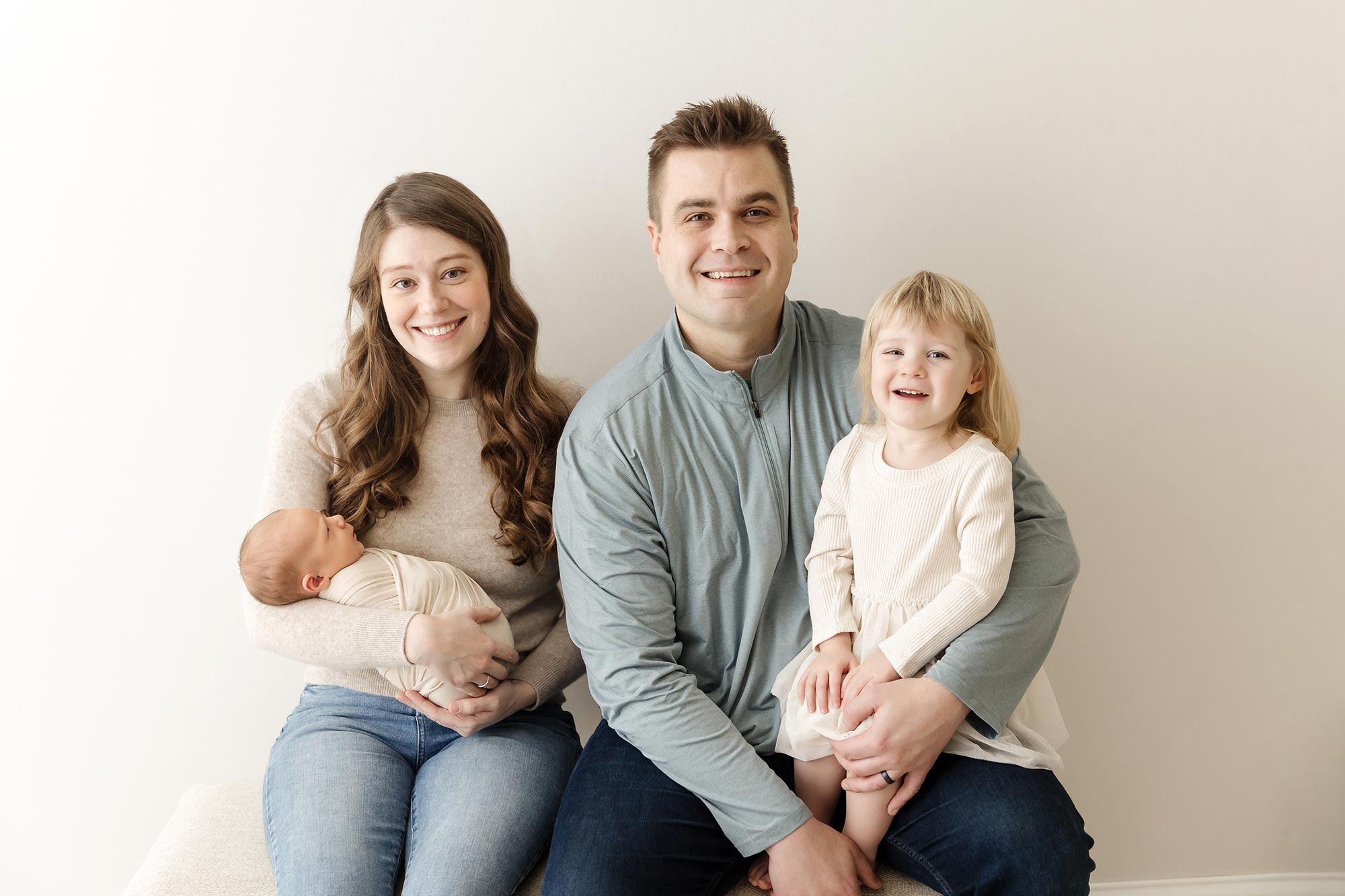 mom dad toddler and newborn sitting together in the studio