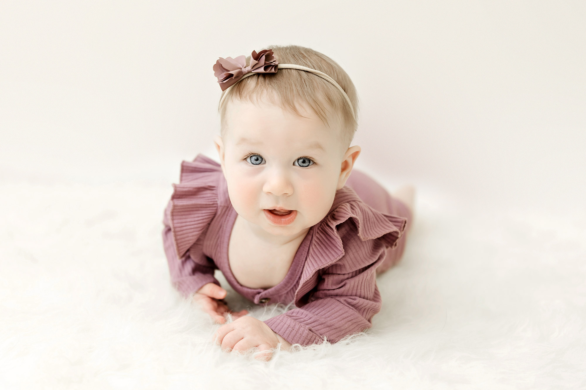 6 month old baby girl lying on stomach on white rug in minneapolis portrait studio