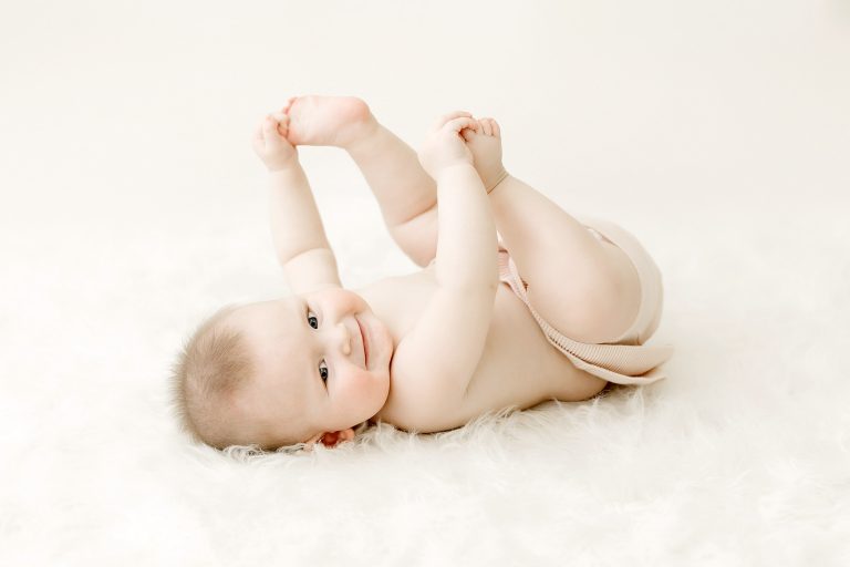 6 month old baby girl on back grabbing toes in twin cities studio