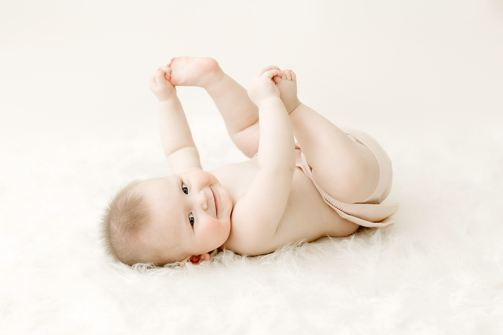 6 month old baby girl on back grabbing toes in twin cities studio