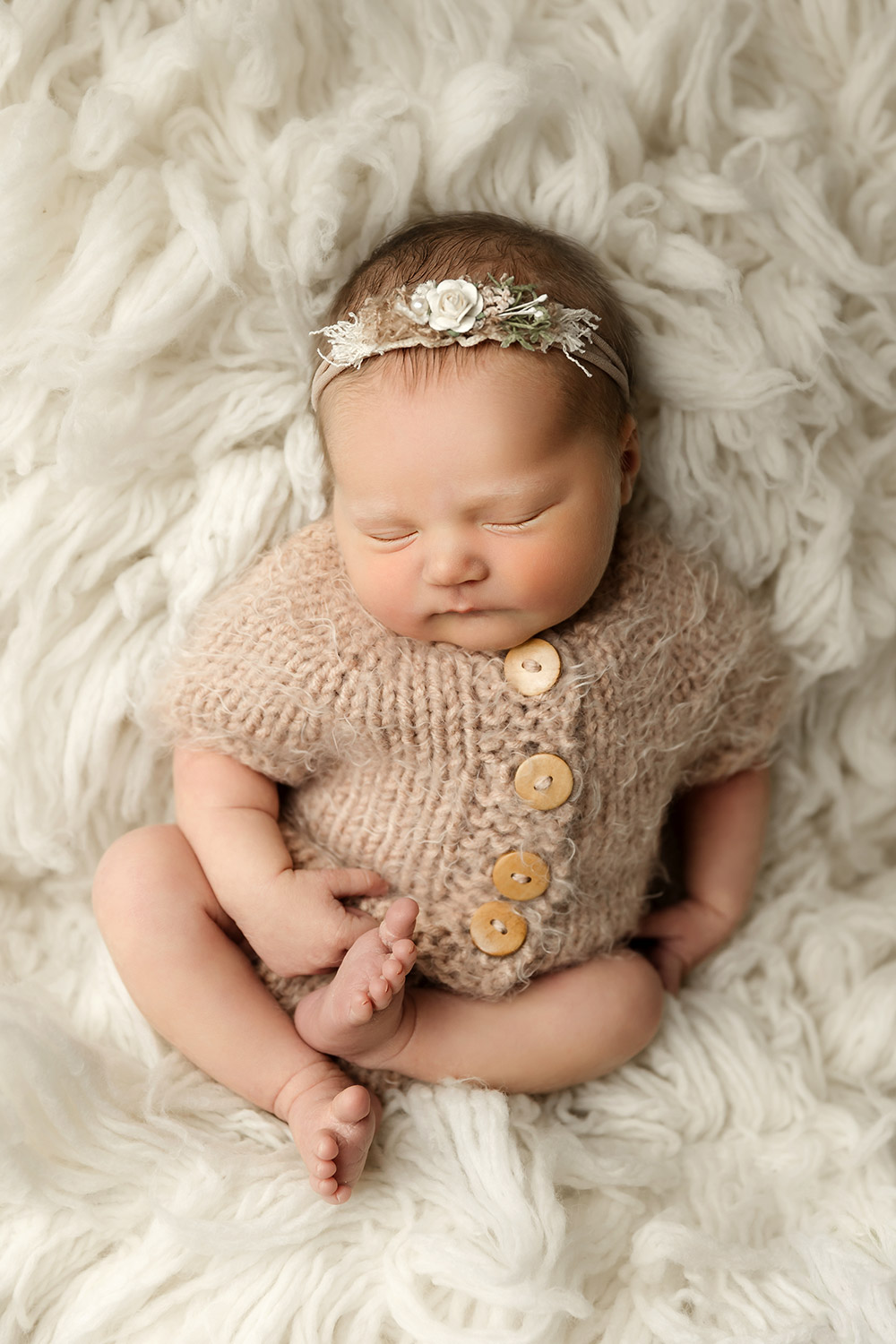 newborn baby girl sleeping on white fluffy rug