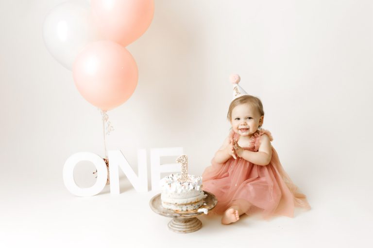 one year baby girl in pink dress with balloons in minneapolis portrait studio