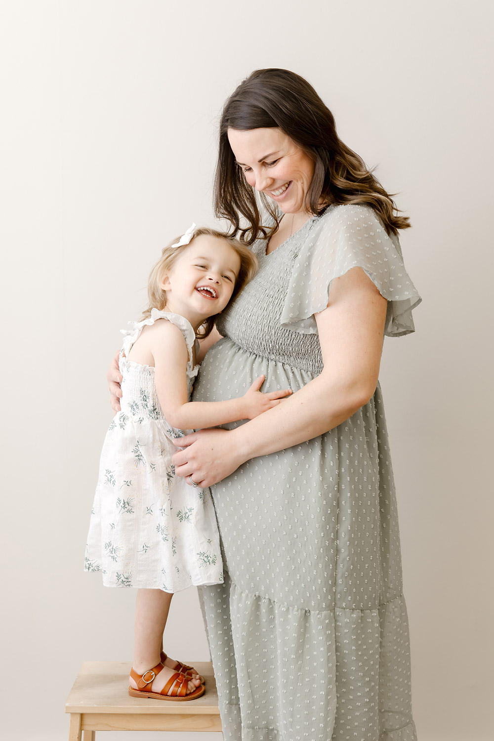 pregnant mom and toddler girl posing in photography studio in twin cities mn