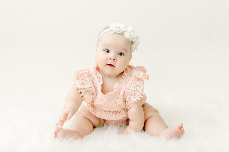baby girl sitting on white rug for her sitter milestone session in portrait studio near Blaine mn