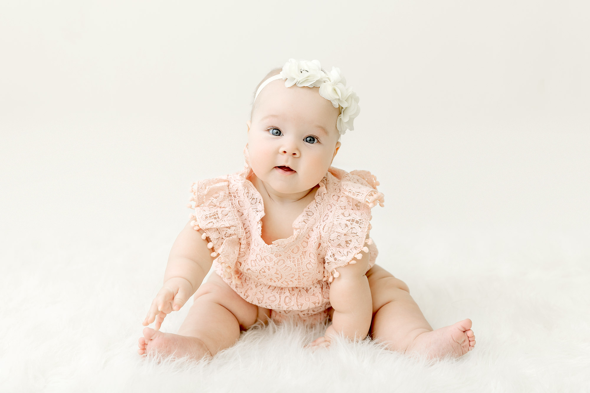 baby girl sitting on white rug for her sitter milestone session in portrait studio near Blaine mn