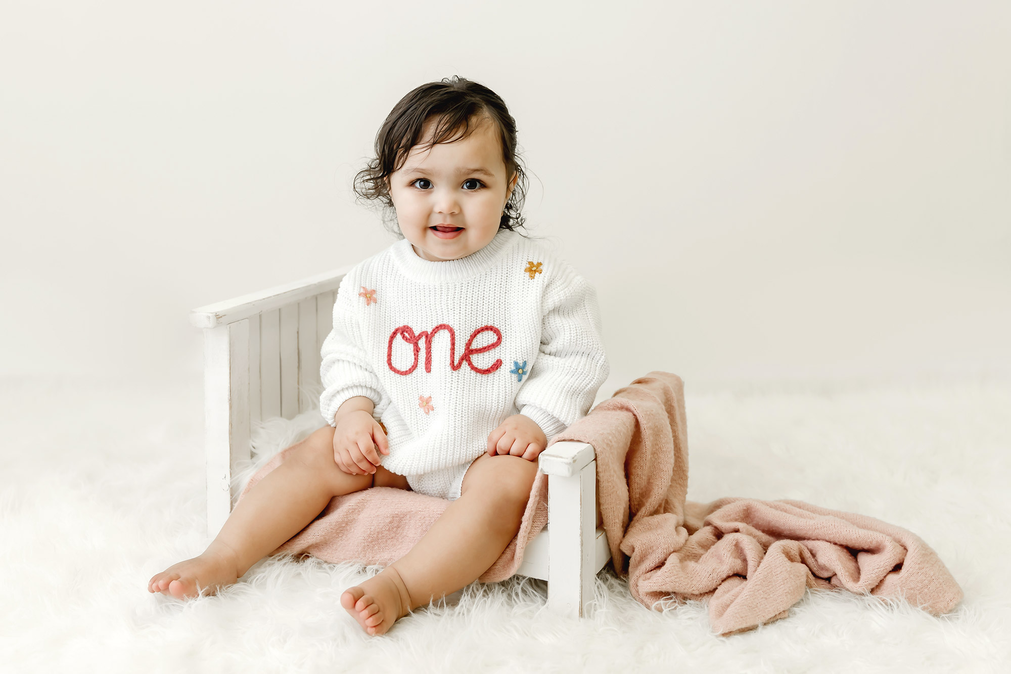 one year old baby girl sitting on prop bed in baby portrait studio minnesota