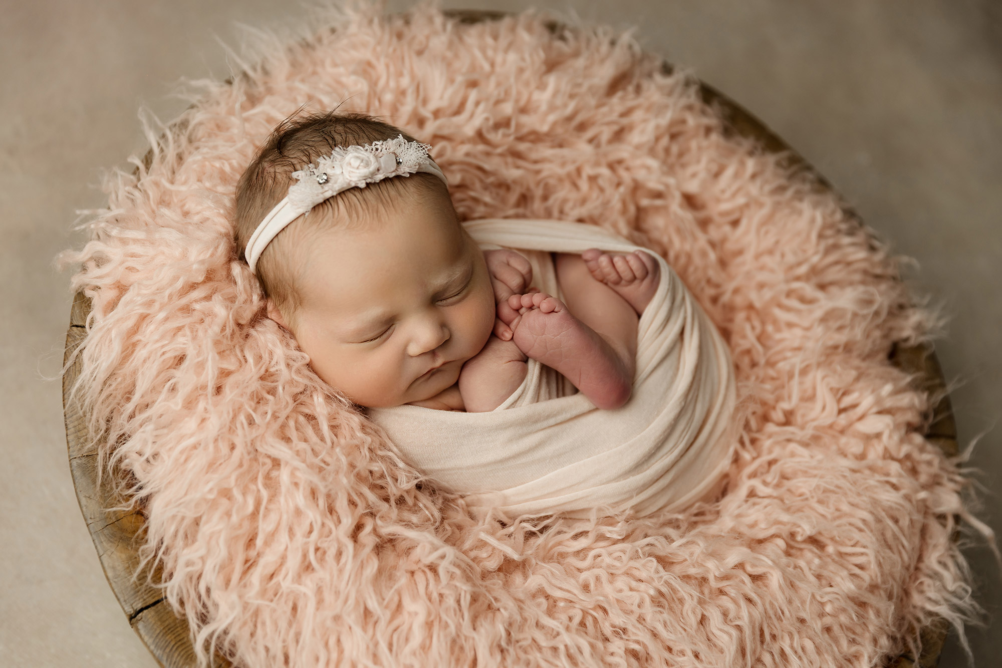 newborn girl wrapped in pink swaddle in bowel