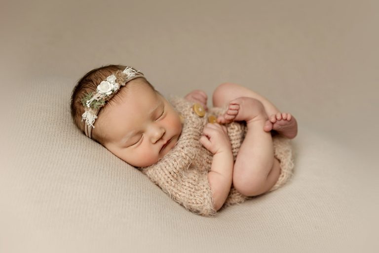 newborn girl with flower headband sleeping on blanket