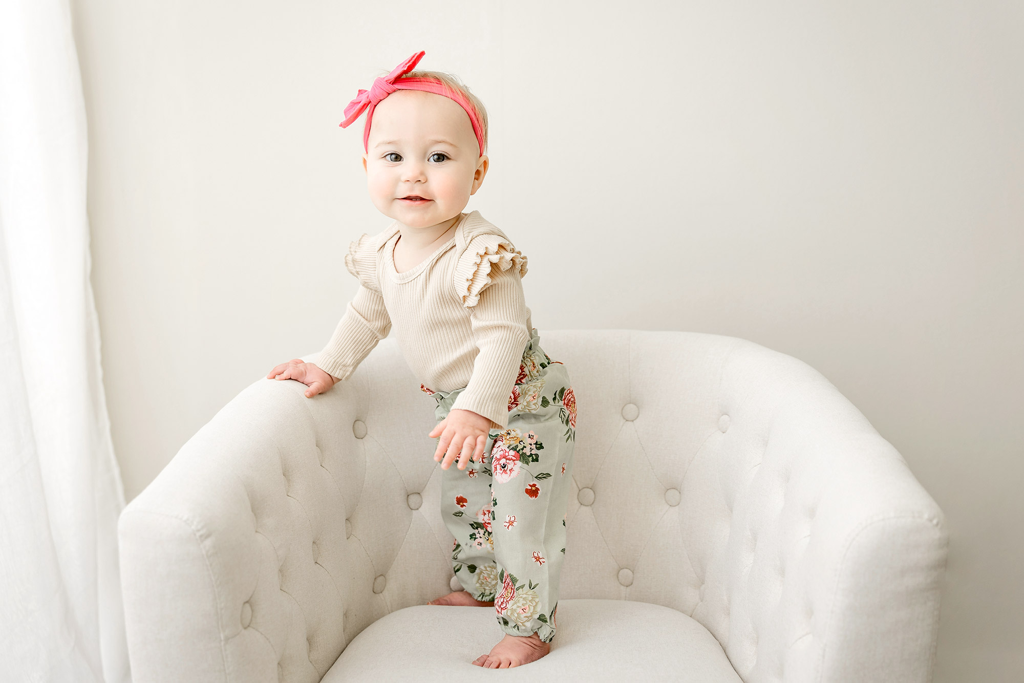 one year baby girl standing in chair in portrait studio in minneapolis mn