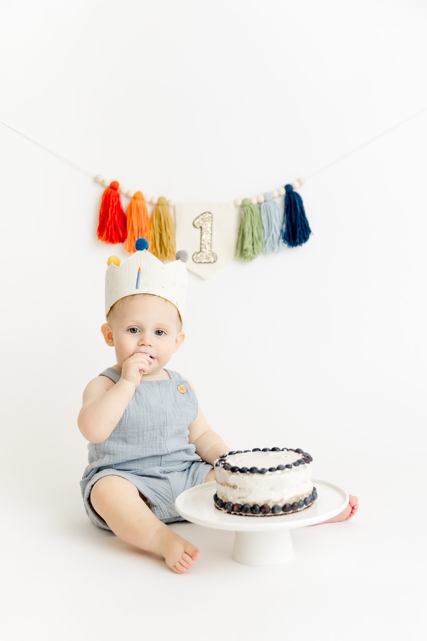 one year baby boy with cake on white background in baby photography studio minneapolis mn