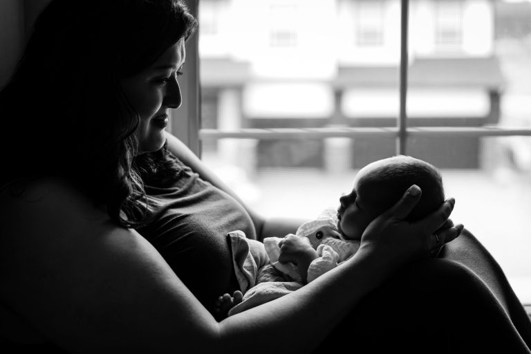 mom sitting in window holding newborn baby in orono mn
